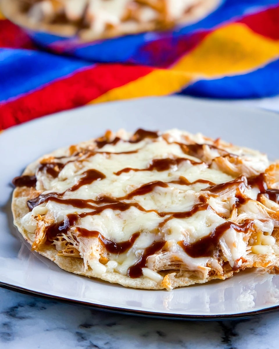 A single tostada is shown on a white plate, with a visible three-layer structure: the bottom layer is a light beige crispy tortilla, the middle layer is a reddish-brown shredded chicken covered in melted white cheese that is stringy and soft, and the top layer is drizzles of dark brown sauce scattered unevenly over the cheese. The edges of the cheese are slightly browned and crispy, melting over the tortilla edges. The background includes a colorful striped cloth and a baking sheet with more similar tostadas in soft focus. The surface is a white marbled texture. photo taken with an iphone --ar 4:5 --v 7