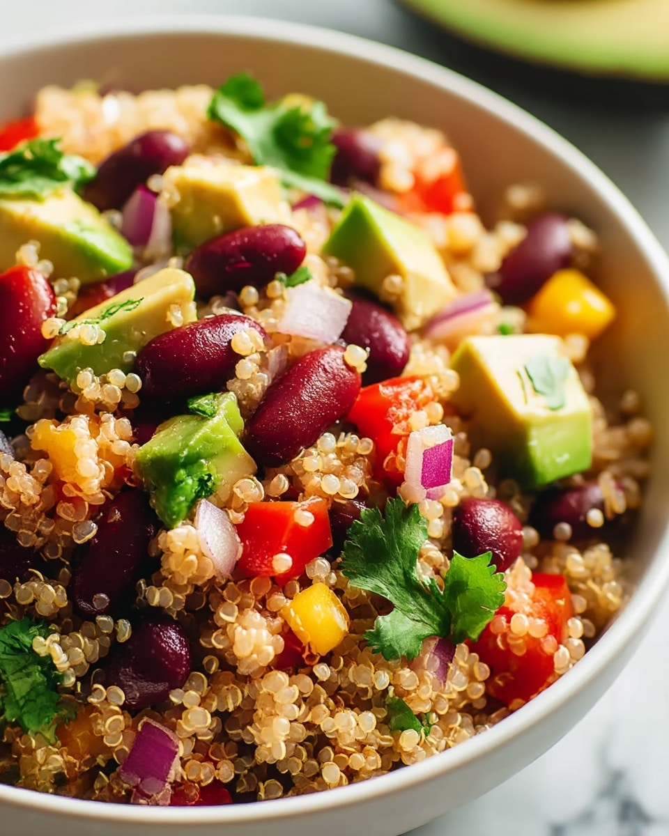 A close-up of a white bowl filled with a quinoa salad showing about three layers: at the base is a light beige, fluffy and round quinoa layer spread evenly; mixed into this are shiny dark purple kidney beans and small diced red tomatoes adding bright red spots; scattered on the top are chunks of light green avocado, small yellow bell pepper pieces, red onion bits with pale purple color, and fresh dark green cilantro leaves, all placed against a white marbled texture background. photo taken with an iphone --ar 4:5 --v 7