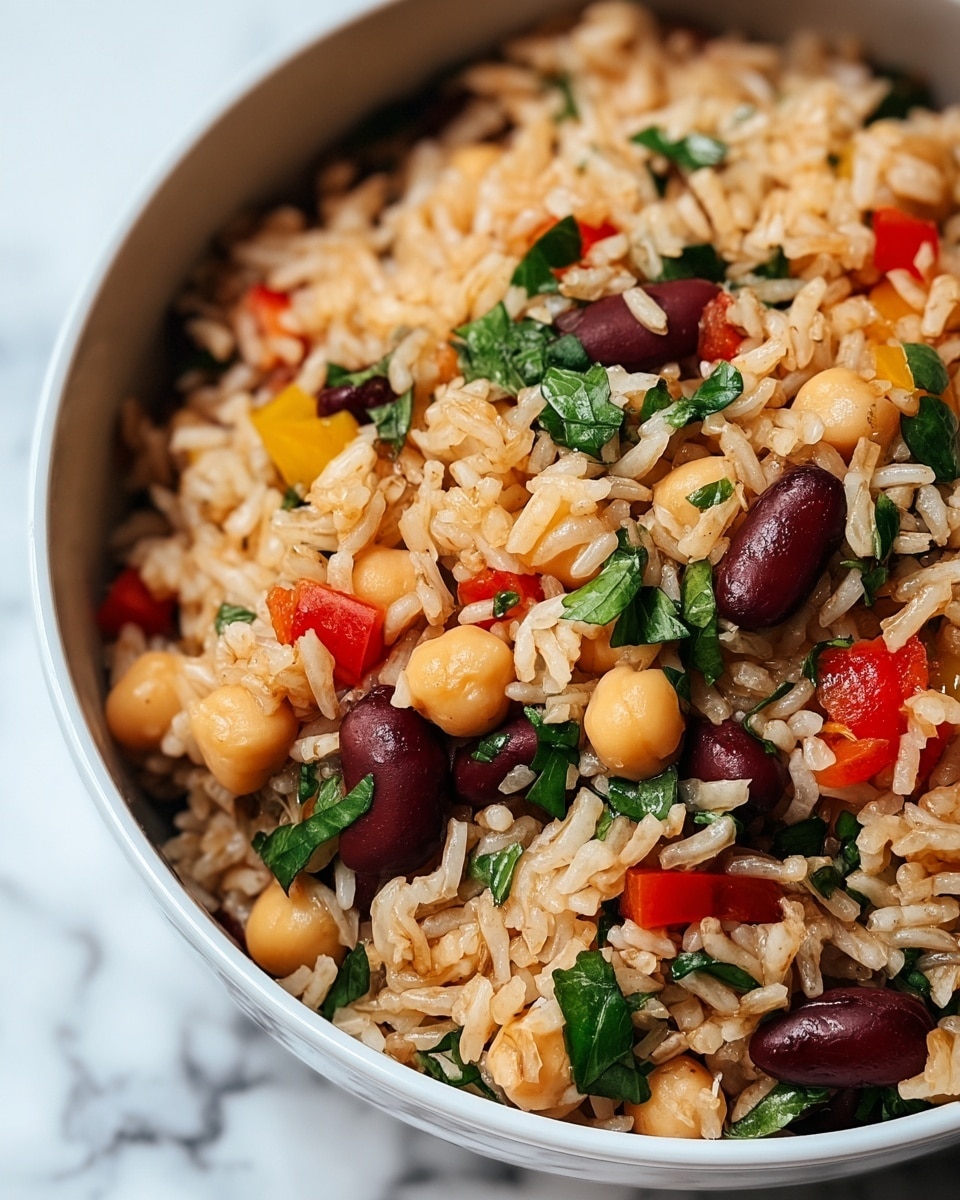 A close-up view of a bowl filled with cooked rice mixed with chickpeas, red kidney beans, chopped red and yellow bell peppers, and fresh green leafy herbs. The rice grains are light brown and well-separated, while the beans and chickpeas add round, plump shapes in beige and dark red colors scattered evenly throughout. Bright green herb leaves are mixed in and rest gently on top, adding fresh color contrast. The bowl is white with a smooth edge, set on a surface with a white marbled texture. photo taken with an iphone --ar 4:5 --v 7