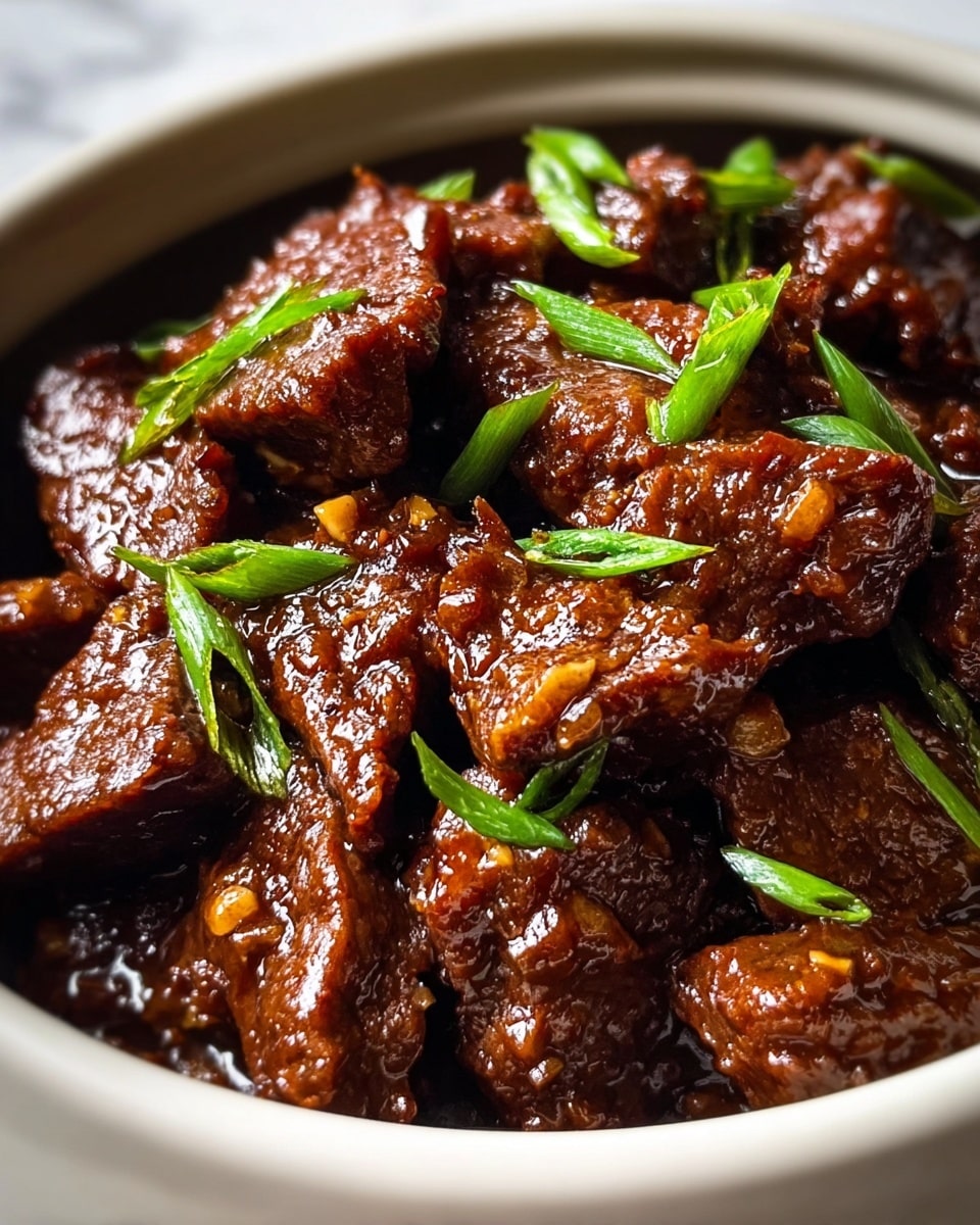 The image shows a close-up of a dish with many pieces of cooked dark brown beef, each piece coated in a glossy, thick sauce. Small, bright green chopped scallions are scattered evenly over the beef, adding a fresh pop of color. The beef looks tender and slightly textured, with bits of finely chopped garlic or onion visible in the sauce. The food is served in a white bowl, and the background is a white marbled texture. photo taken with an iphone --ar 4:5 --v 7