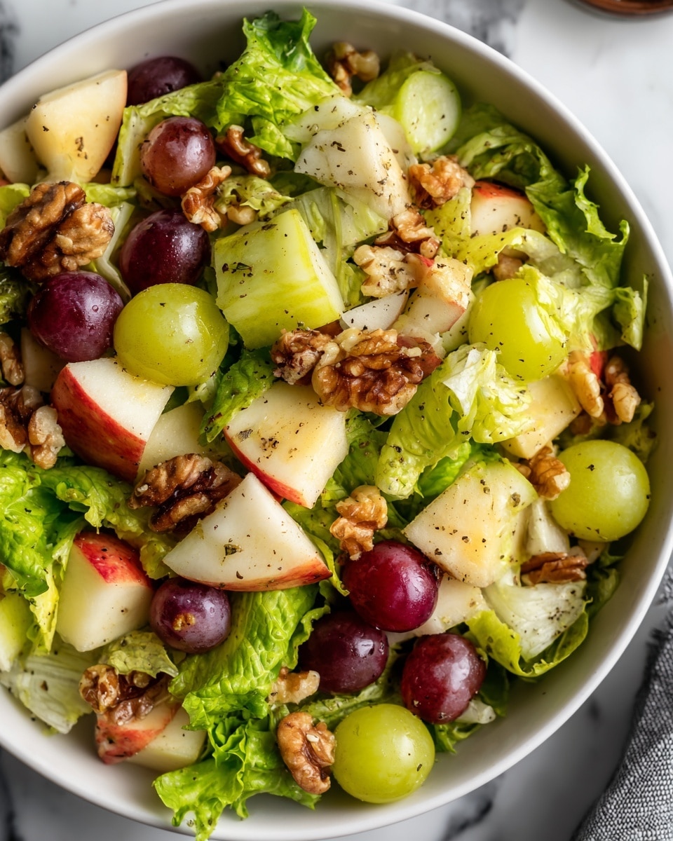 A close-up view of a white bowl filled with a fresh salad on a white marbled surface, the salad has a base layer of green leafy lettuce with soft, slightly ruffled edges, topped with several layers of chopped fruits including pale green melon pieces, red apple cubes with skin showing red and cream colors, green and purple grapes, and scattered brown walnut halves. The fruits and nuts are lightly sprinkled with cracked black pepper, giving texture contrast. The bowl is seen from the top, showing all ingredients mixed evenly. Photo taken with an iphone --ar 4:5 --v 7