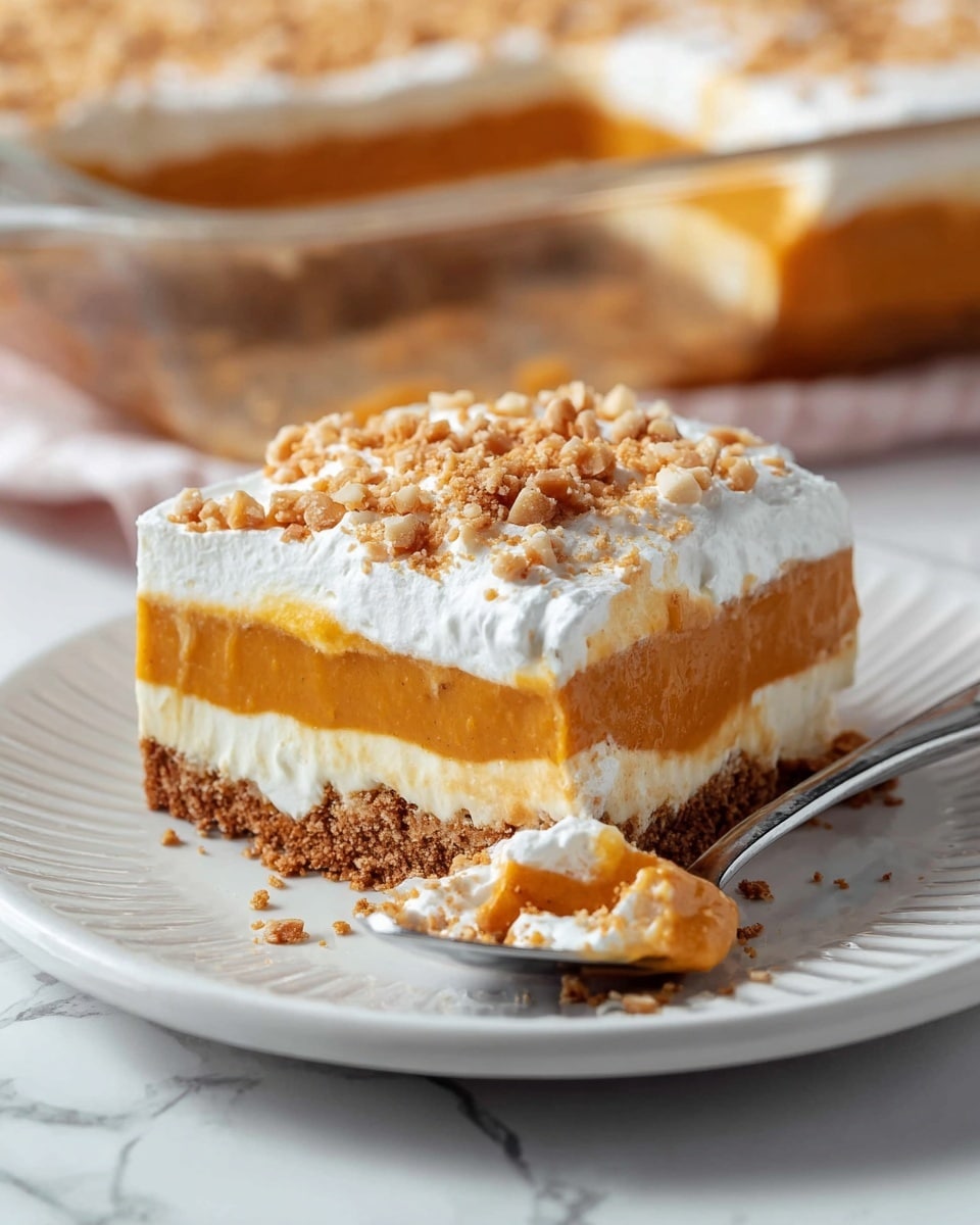 A slice of layered pumpkin dessert sits on a white plate with ridged edges, placed on a white marbled surface. The dessert has four layers: a dark brown crumbly crust at the bottom, a smooth white cream layer above it, followed by a thick orange pumpkin layer, and topped with a fluffy white whipped cream layer sprinkled with small crushed nut pieces in light brown. A small piece of the dessert has been scooped onto a silver spoon lying in front, showing the same layers clearly. In the background, part of the full dessert in a glass dish is slightly out of focus. Photo taken with an iphone --ar 4:5 --v 7