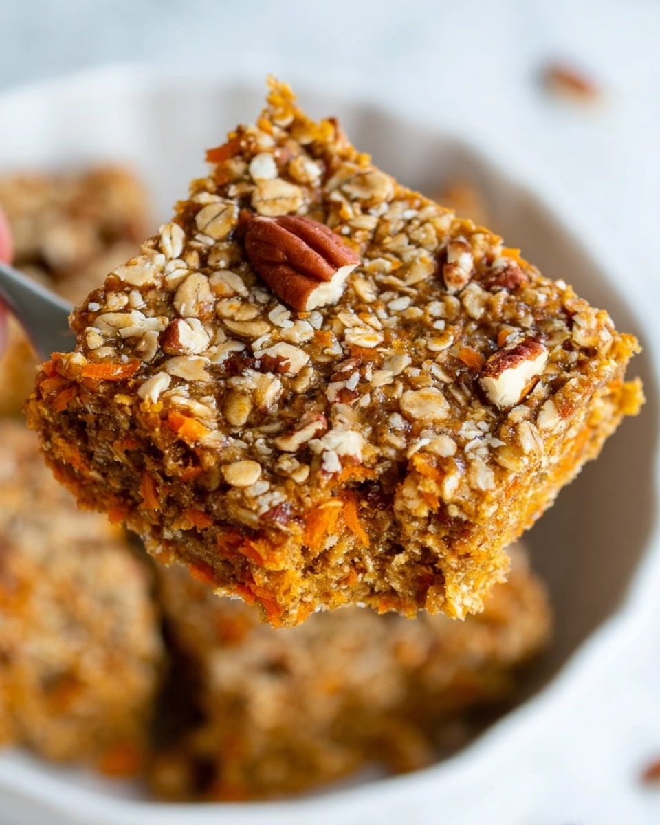 A close-up of a square oat bar held above a white dish, showing a dense texture made of oats and small pieces of orange carrot mixed throughout. The bar has a rough top layer sprinkled with whole and chopped pecans and more oats, giving a crunchy look. The oat bar is thick, about two layers deep, with the orange carrot bits visible inside. The white dish below holds more oat bars, slightly out of focus, set on a white marbled surface. Photo taken with an iphone --ar 4:5 --v 7