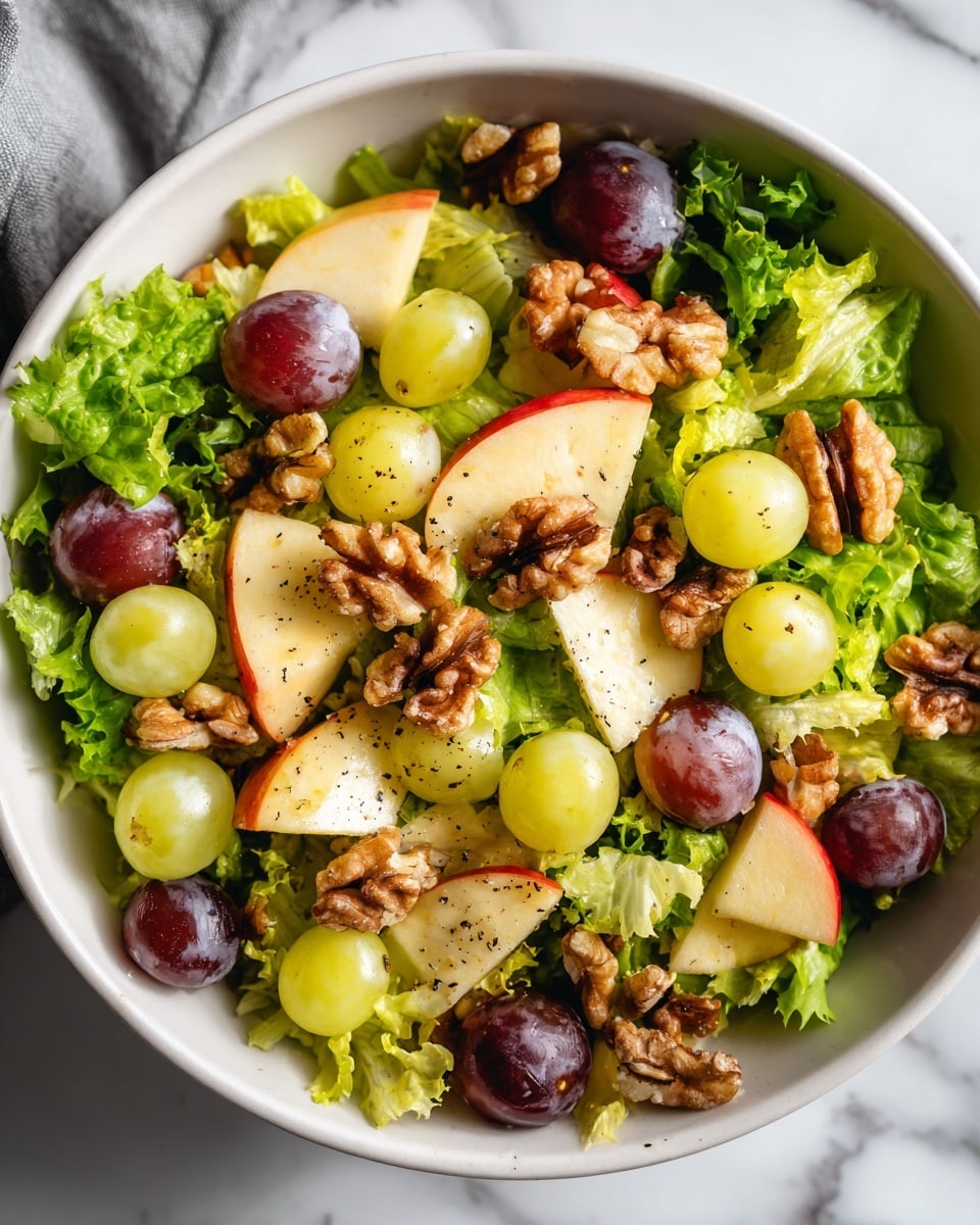 The image shows a white bowl filled with a fresh salad, starting with a base layer of green lettuce leaves that have a slightly ruffled texture. On top of the lettuce, there are several pieces of light green and red apple slices, cut into small wedges with smooth skin and a crisp texture. Scattered throughout the salad are pale green and deep purple grapes, adding rounded shapes and shiny surfaces. Finally, toasted walnut halves are sprinkled over the salad, adding a rough, brown, and crunchy texture with small specks of black pepper visible on the ingredients. The bowl sits on a white marbled surface, and the lighting highlights the fresh, mixed colors of the salad. photo taken with an iphone --ar 4:5 --v 7