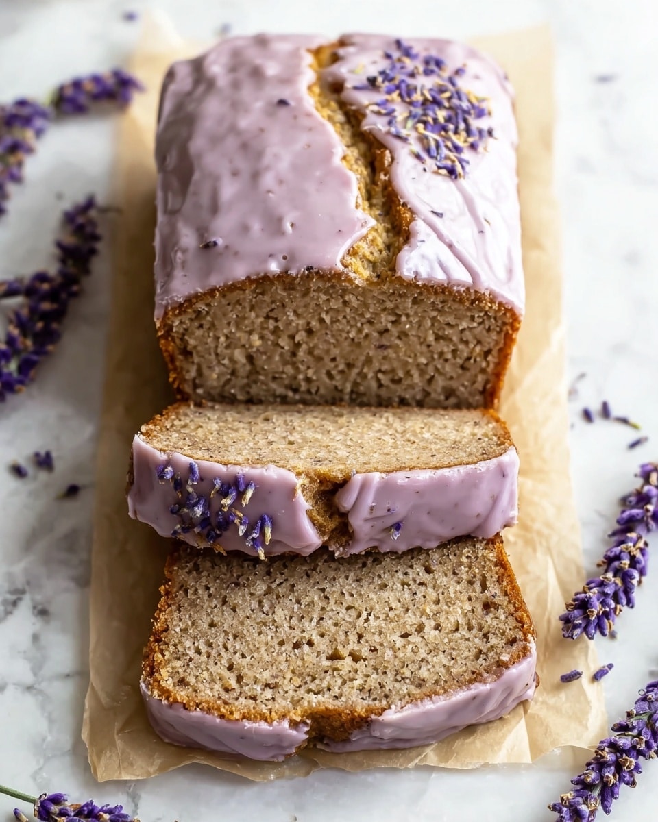 A loaf of moist, textured lavender bread is shown with two slices cut and laid in front. The top layer features a thick, creamy light purple glaze with visible speckles and a cracked line in the middle, decorated with small purple lavender buds scattered on one side. The bread crumb inside is light brown with a slightly coarse texture. The loaf rests on a piece of light beige parchment paper, placed on a white marbled background with sprigs of fresh lavender flowers scattered around. Photo taken with an iphone --ar 4:5 --v 7