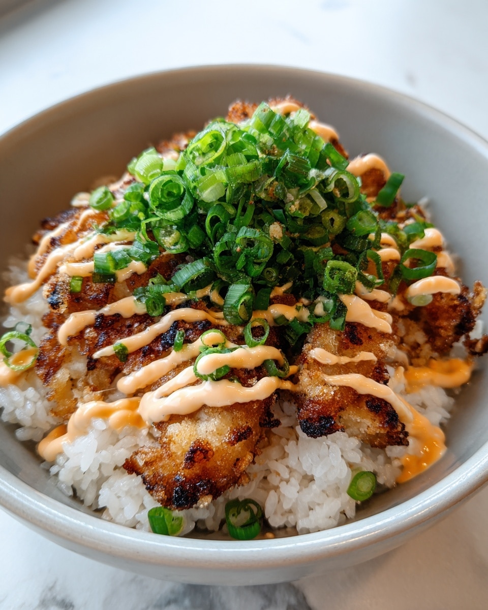 A bowl holds three main layers: at the bottom is a bed of fluffy white rice with some scattered thin green onion slices; on top of the rice are several pieces of crispy, golden-brown fried chicken with slight char marks, giving a crunchy texture; drizzled over the chicken are light, creamy zigzag lines of pale orange sauce; the dish is finished with a thick pile of bright green chopped scallions centered on the chicken, adding fresh color and texture, all set in a white bowl on a white marbled surface. photo taken with an iphone --ar 4:5 --v 7
