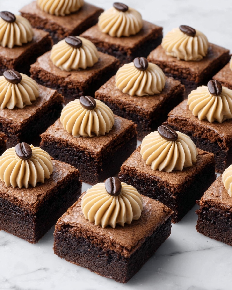 The image shows several square brownies arranged neatly on a white marbled surface. Each brownie is thick with a dark brown, slightly cracked and textured top layer. On top of each brownie sits a small, light tan swirl of creamy frosting, piped with ridges, giving it a soft, fluffy look. Each frosting swirl is finished with a single dark brown coffee bean placed on top, adding a smooth and shiny detail. The rows of brownies are evenly spaced, creating a clean and orderly appearance. photo taken with an iphone --ar 4:5 --v 7